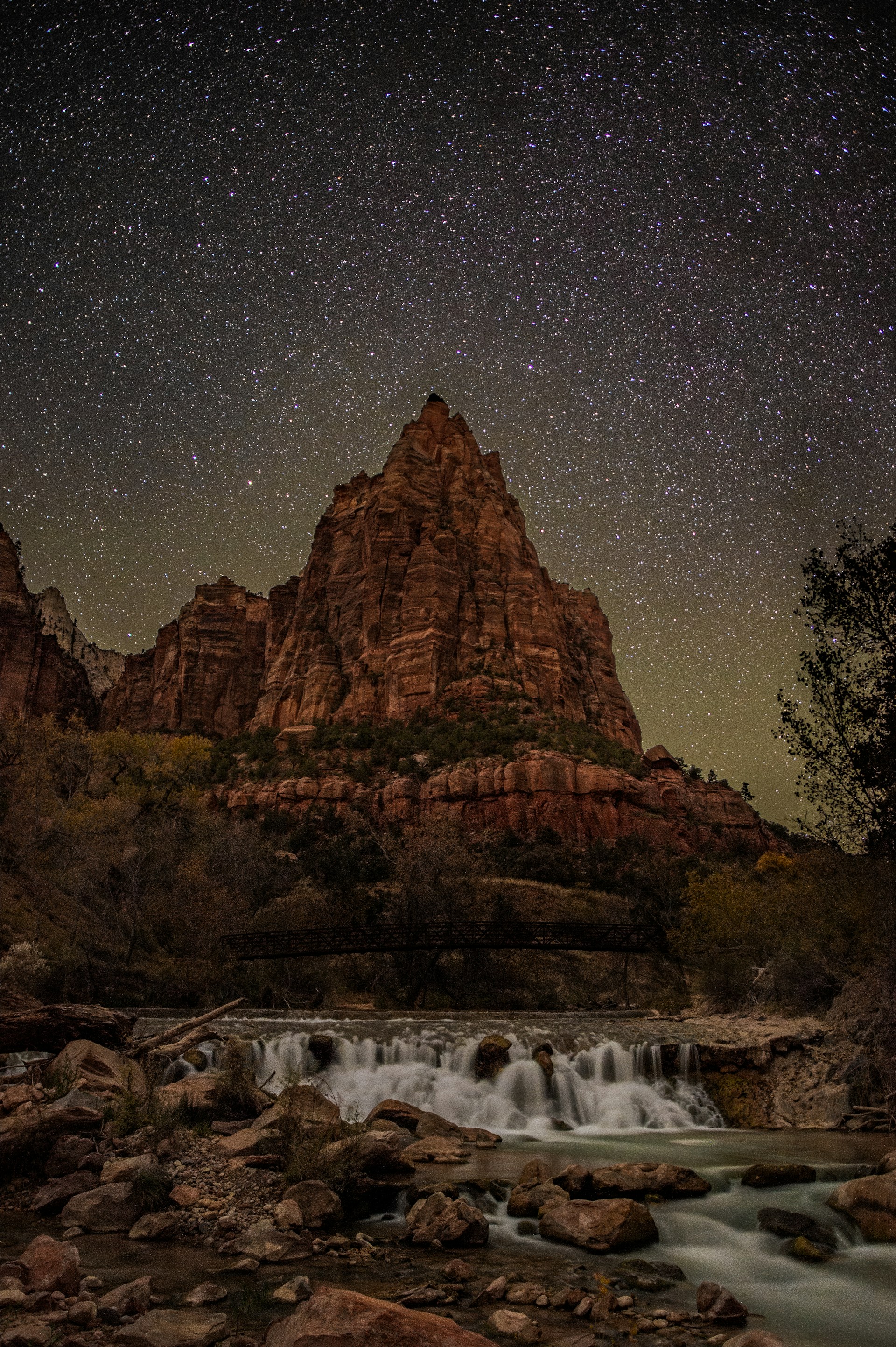 Zion National Park at night with starry sky over red cliffs and the Virgin River